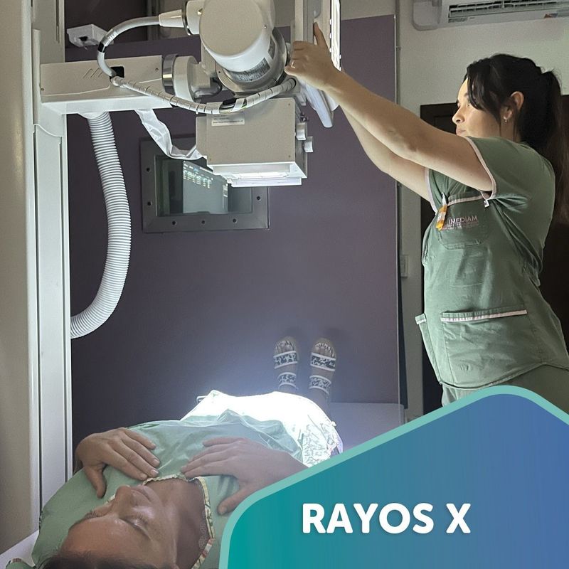 Técnica ubicando el equipo de rayos X sobre un paciente